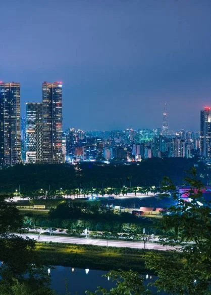 강과 고층 빌딩, 도시의 불빛이 보이는 세로 구도의 야경