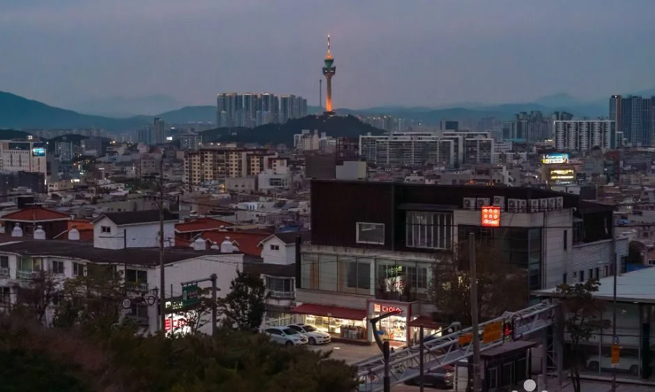해 질 무렵의 어두운 하늘 아래 시가지 너머로 보이는 대구 83타워