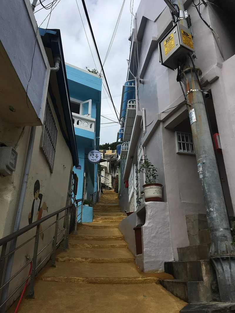 양쪽 건물 사이 좁은 오르막 골목과 벽에 설치된 배관