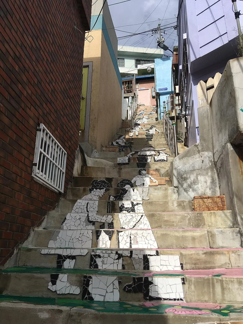 벽돌 담과 창이 있는 건물 사이로 이어진 계단 골목