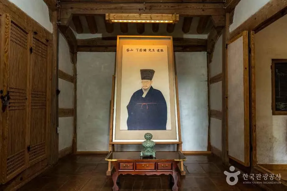 전통 방 안 벽 앞에 세워진 인물 초상화와 작은 상