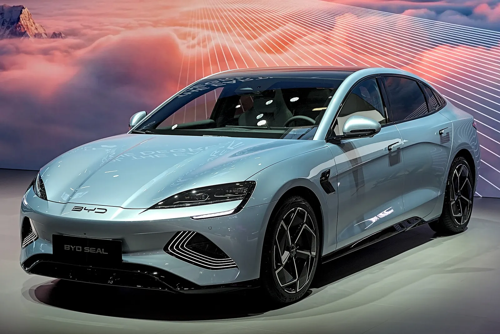 푸른빛이 도는 은회색 BYD 씰 전기 세단의 전면과 측면, 전시장 조명