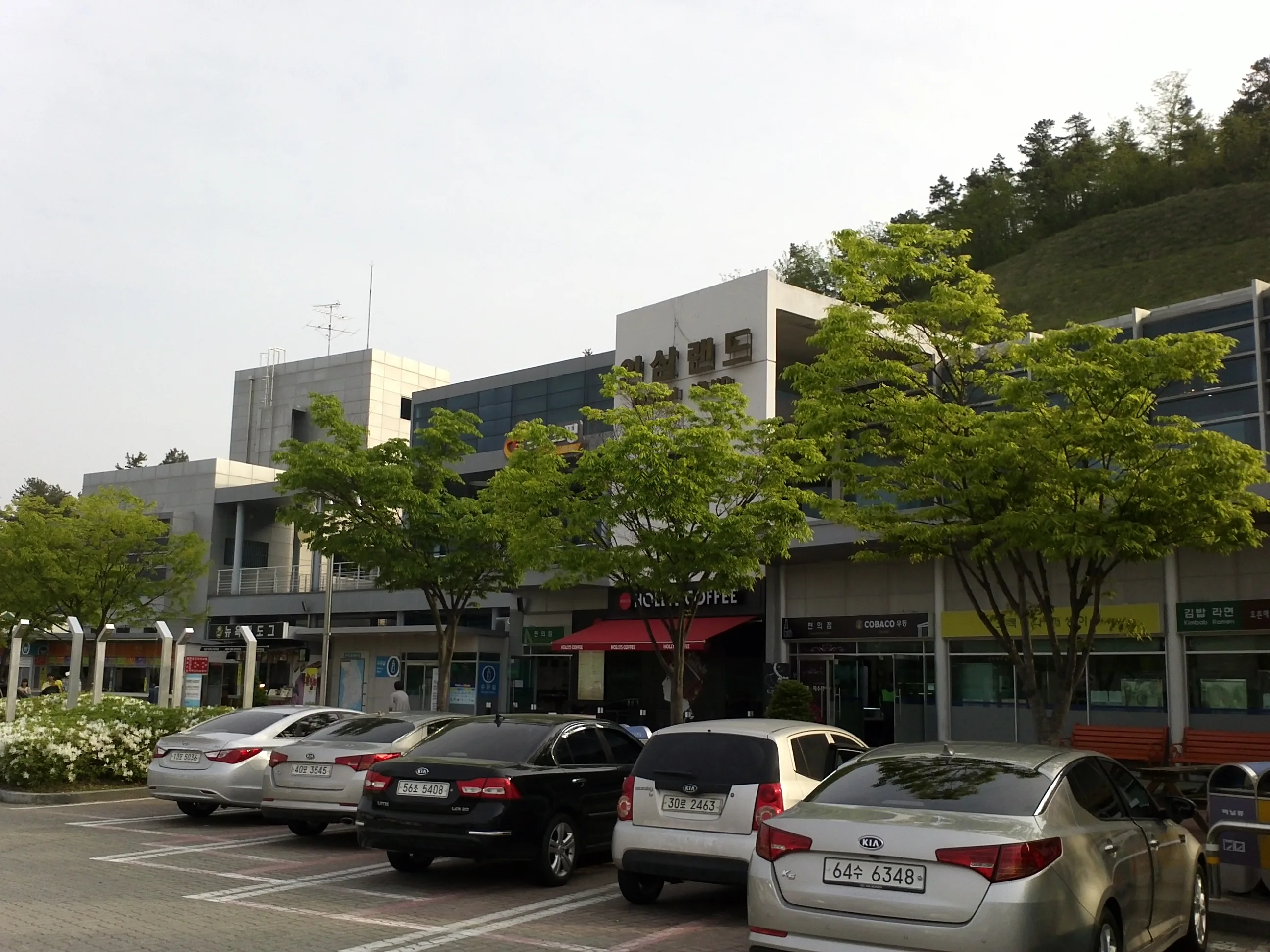 통영대전고속도로 인삼랜드 휴게소 건물과 주차된 승용차들, 뒤로 카페 매장이 보인다