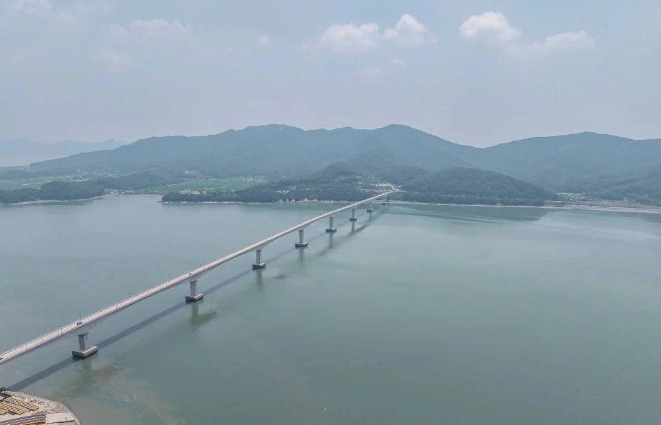 바다 위로 길게 뻗은 석모대교와 강화 본섬 쪽 산을 내려다본 항공 사진