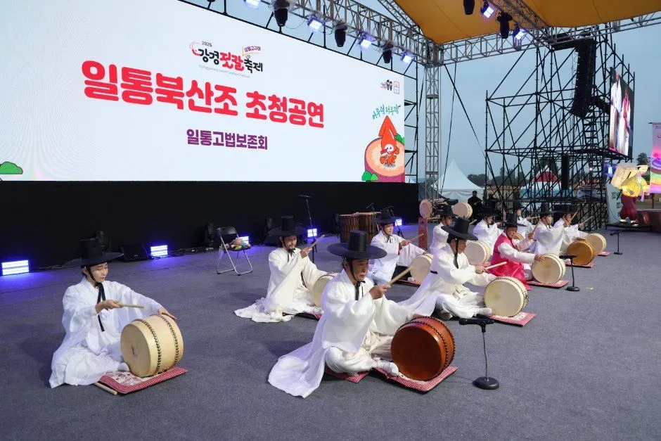 흰 한복을 입은 연주자들이 북을 치는 무대 공연 모습과 뒤쪽 축제 로고 화면