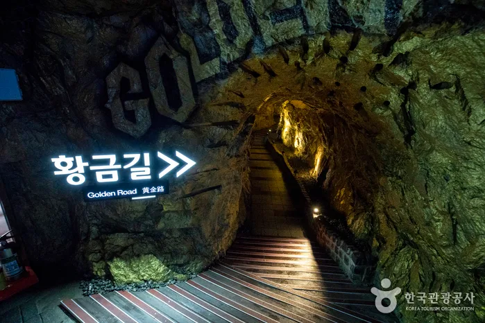황금길 표지판과 황금색 조명이 비추는 동굴 계단