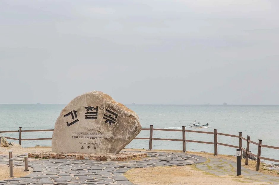 바다를 배경으로 서 있는 간절곶 표지석과 나무 난간