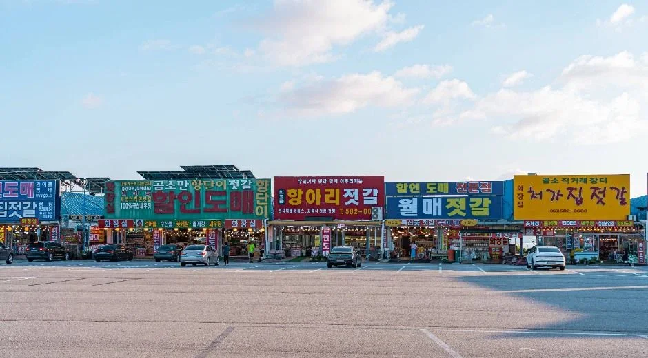 넓은 주차 공간 너머로 젓갈 상점 간판이 이어진 거리