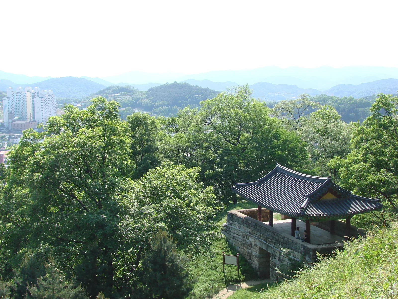 숲과 정자 너머로 공주 시가지 아파트와 산줄기가 보이는 공산성 전망
