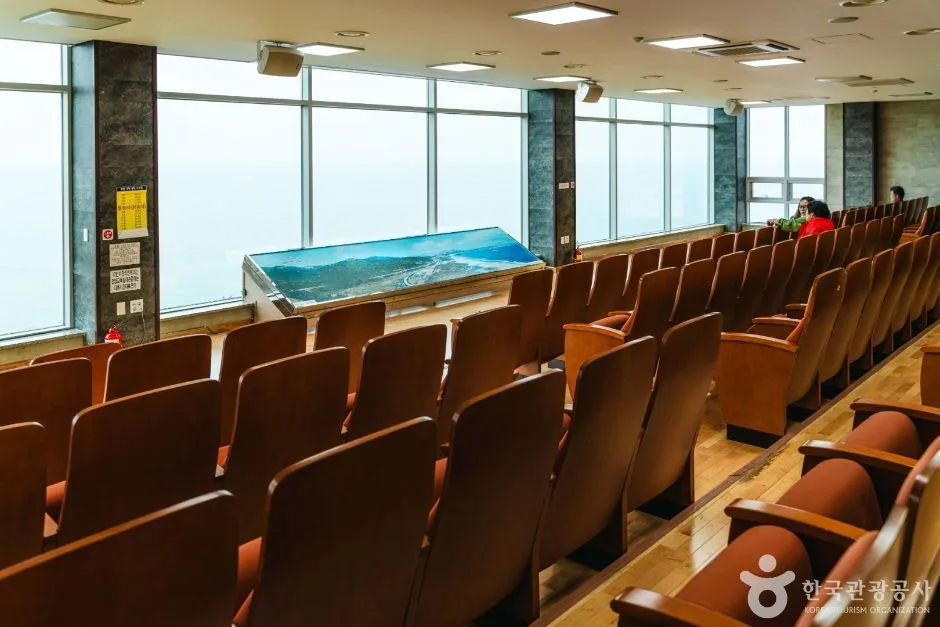 유리창 앞에 극장식 좌석이 놓인 통일전망타워 내부 공간