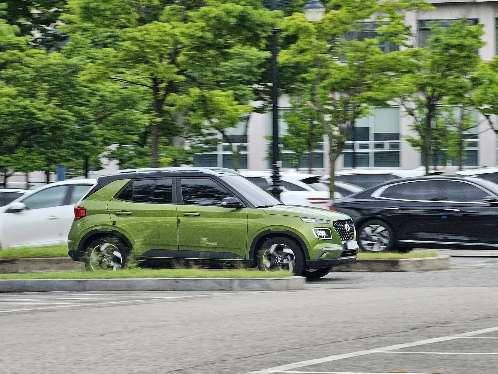 도로변에 서 있는 녹색 현대 베뉴, 소형 SUV 측면