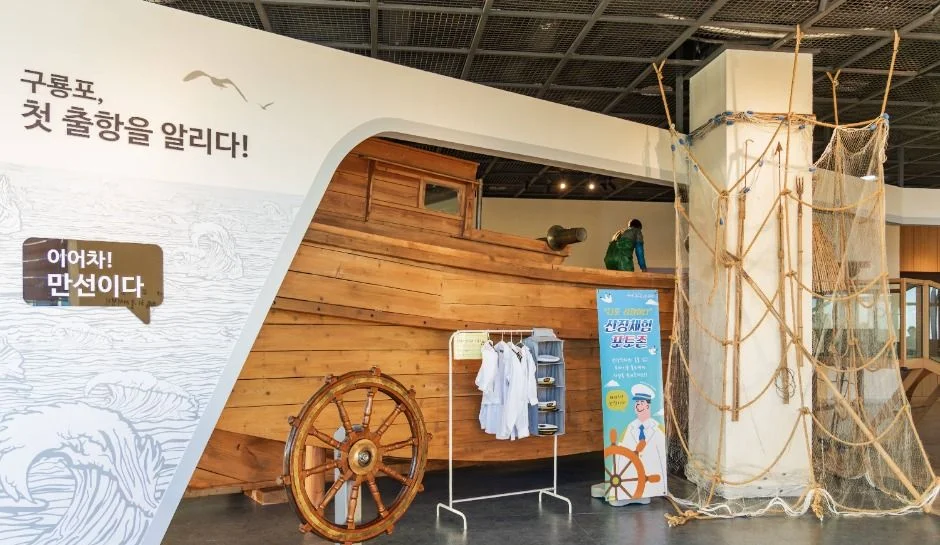 나무 배 모형과 키가 놓인 구룡포 첫 출항 전시 공간