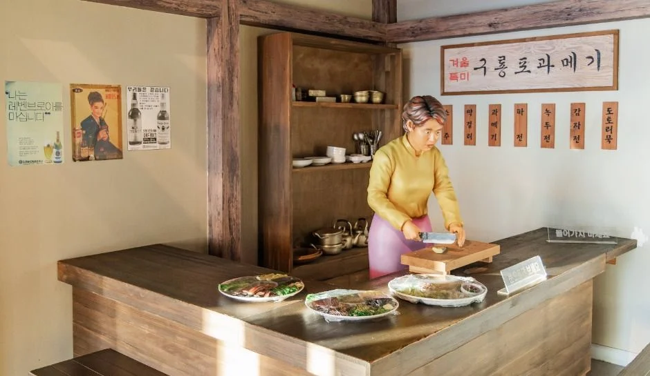 구룡포 과메기 간판 아래 조리대에서 음식을 준비하는 인물 모형