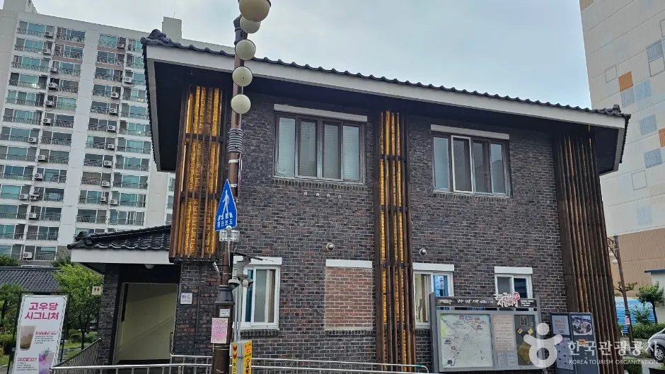 붉은 벽돌 외벽과 나무 문틀이 있는 초원사진관 건물과 뒤편 아파트