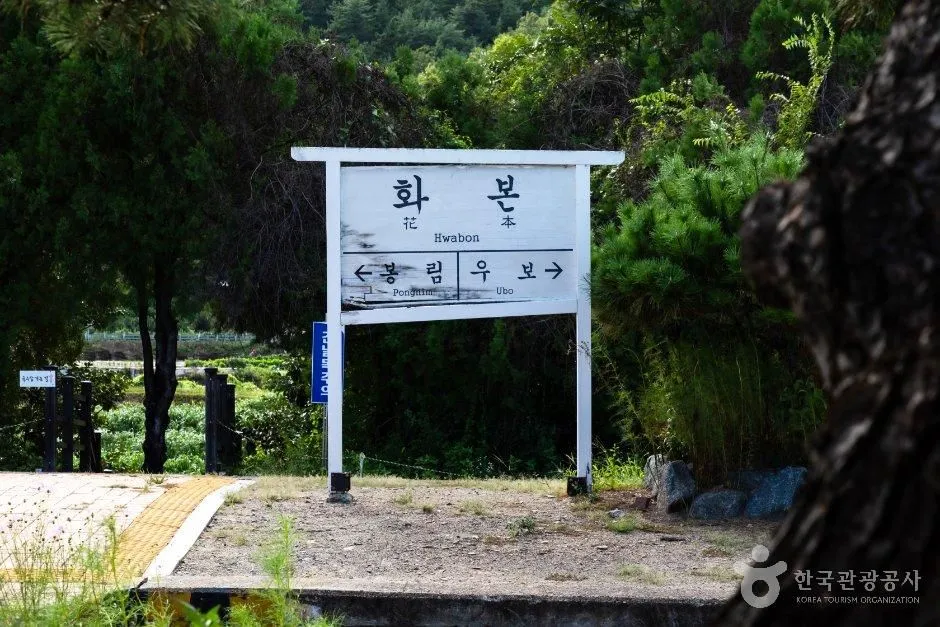 역 이름이 적힌 하얀 표지판 뒤로 철길이 보이는 모습