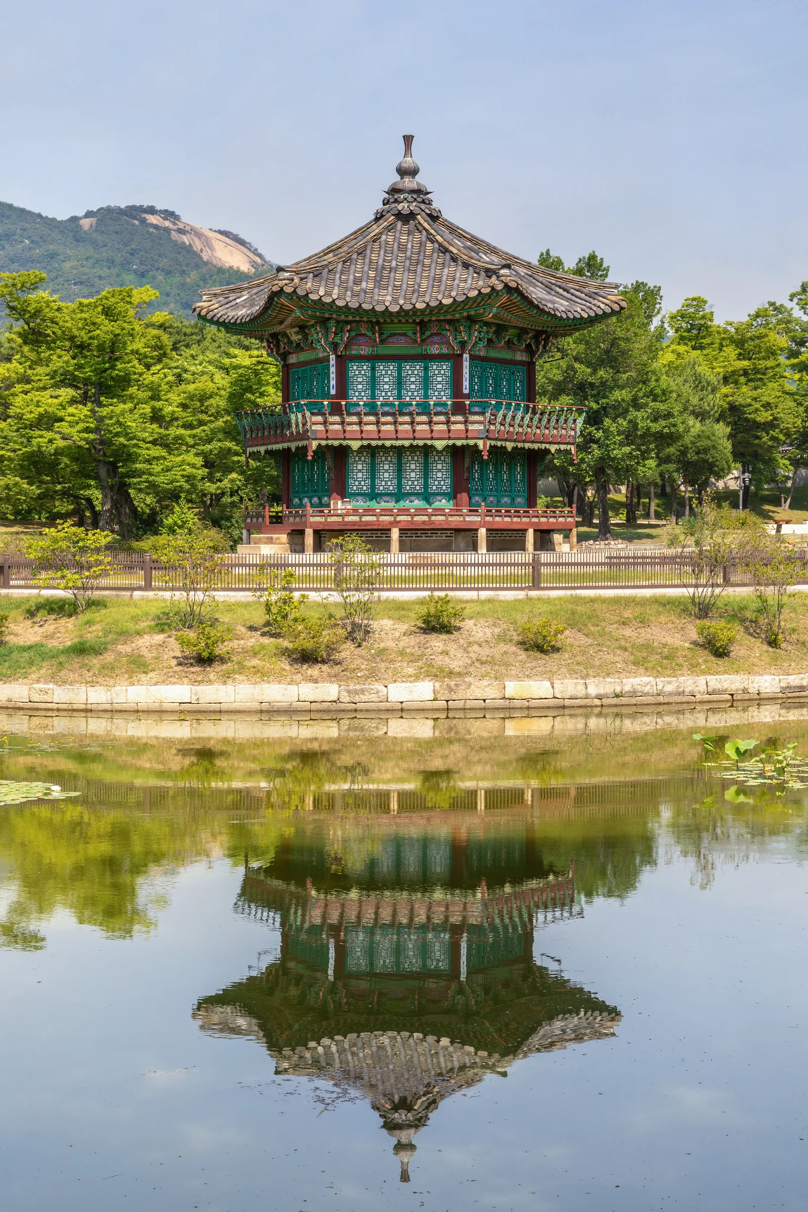 맑은 낮 하늘 아래 연못에 비친 경복궁 향원정 전경
