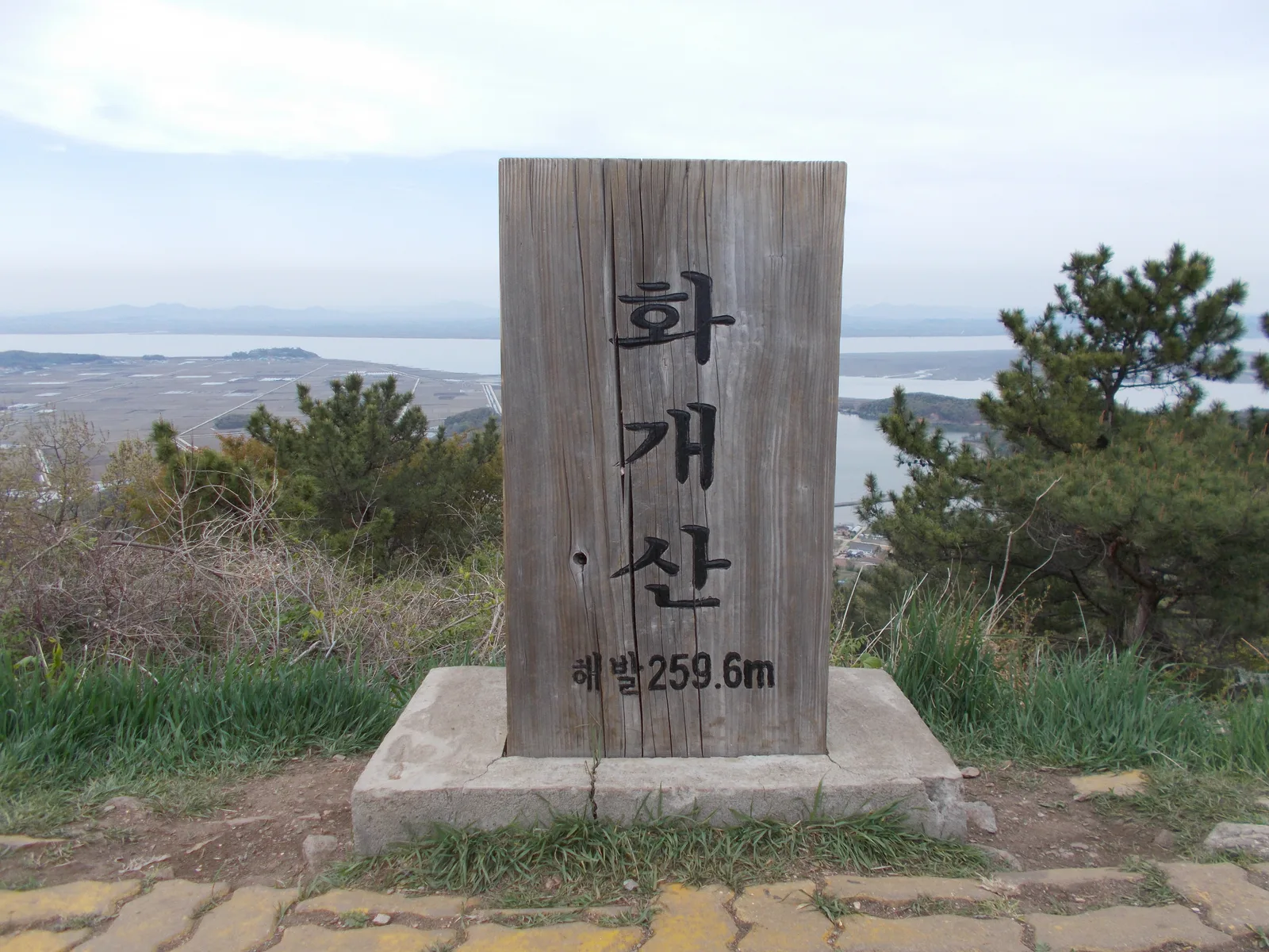 화개산 정상 표지석 뒤로 한강 하구와 갯벌, 저 멀리 들판이 펼쳐진 전경