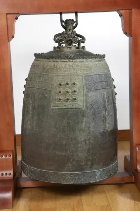목재 받침대 위에 놓인 하동 쌍계사 동종, 표면에 문양과 명문이 새겨져 있다