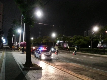 가로등이 켜진 밤 도로에서 경찰차와 경찰관들이 차량을 단속하고 있는 음주단속 현장