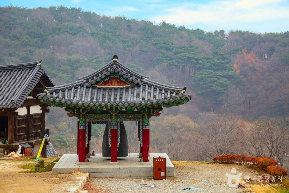 붉은 기둥의 종각과 단풍이 남은 산자락