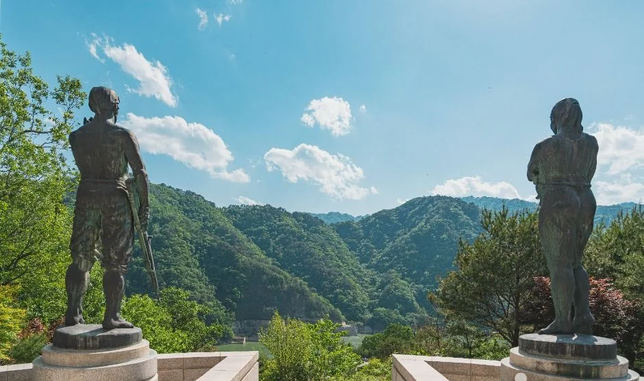 산골짜기를 배경으로 서 있는 두 개의 인물 동상