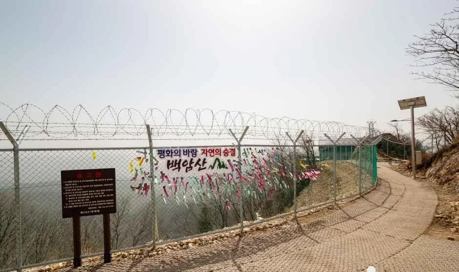 철조망 너머 산길이 이어지고 안내판이 선 전망 구간