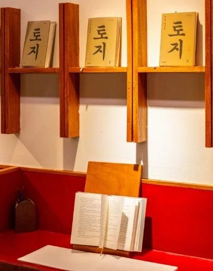 '토지' 글자가 붙은 책장과 펼쳐진 책
