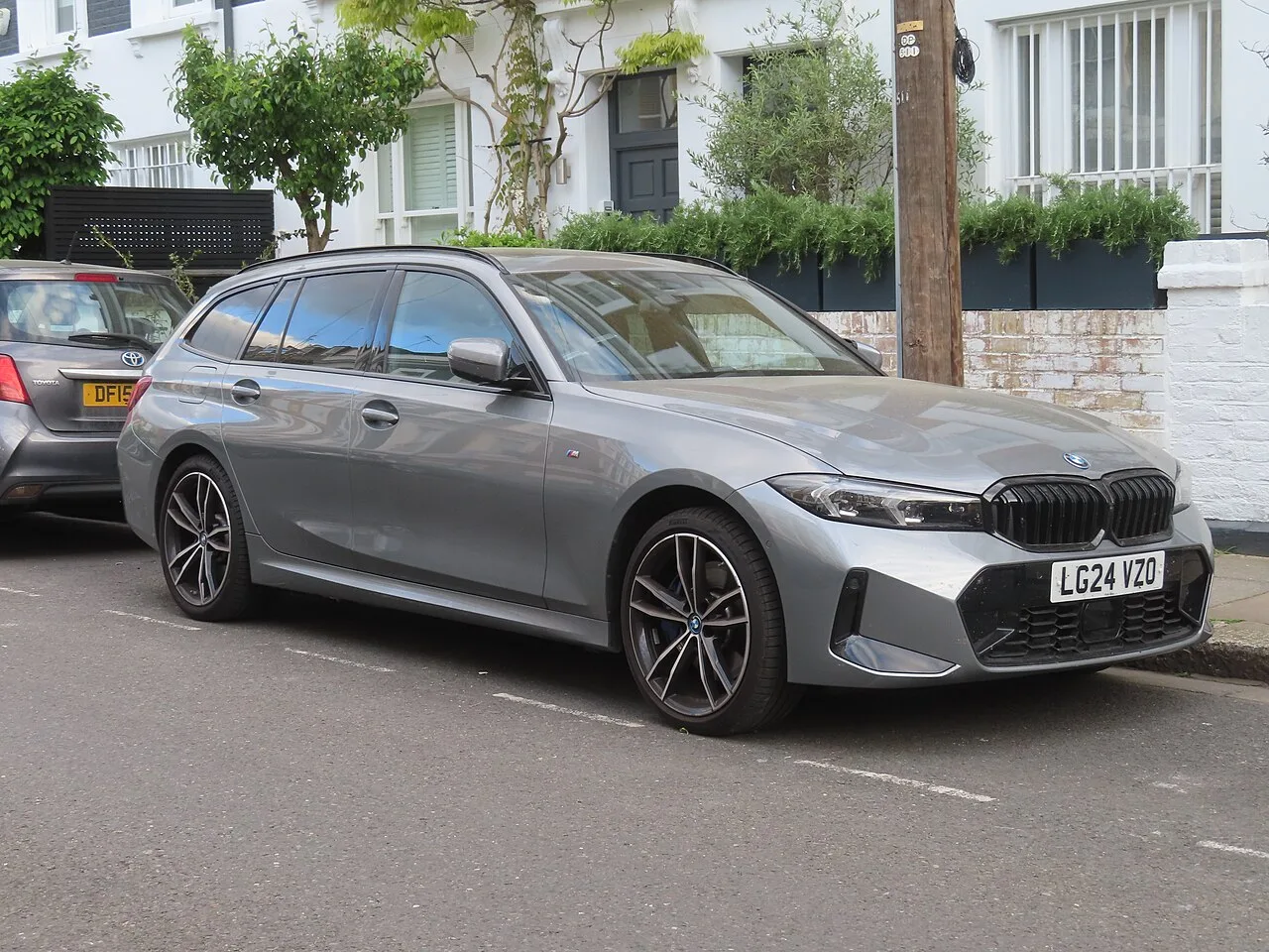회색 BMW 3시리즈 투어링의 전측면, 주택가 도로에 주차된 모습