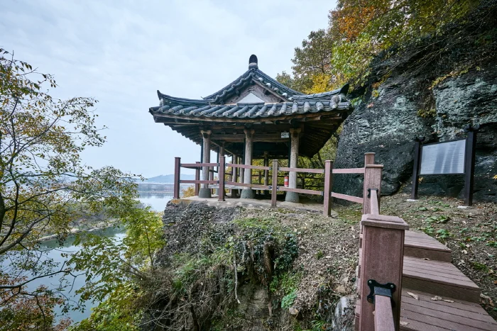 절벽 위 데크 옆에 서 있는 기와지붕의 악양루와 남강