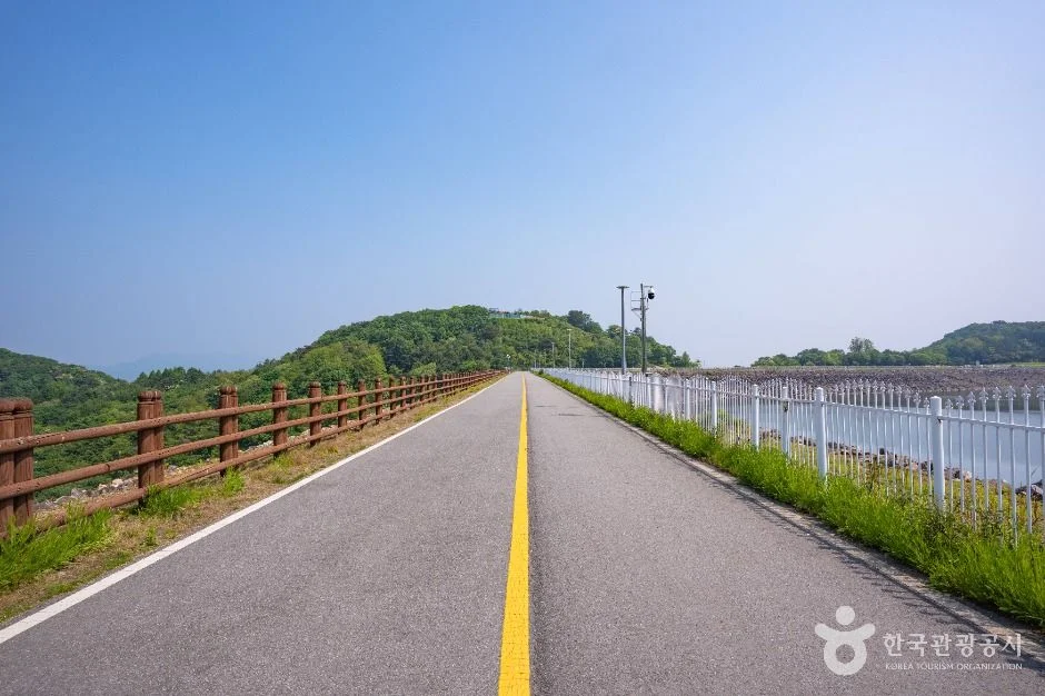 양쪽에 난간이 이어진 호수 둘레 포장도로와 능선