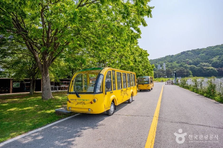 호수 둘레 도로에 서 있는 노란색 전기 순환차