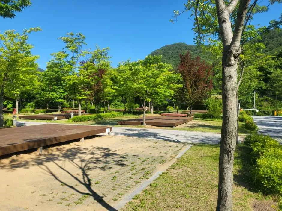 산자락 아래 나무 데크와 파쇄석 바닥을 갖춘 홍천강 오토캠핑장 야영 사이트