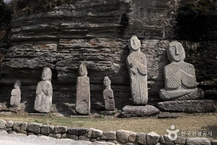 층진 암벽 아래에 줄지어 놓인 운주사 석불들