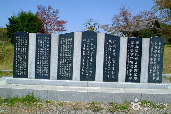 검은 판석에 글이 새겨진 시비 벽과 뒤쪽 정자