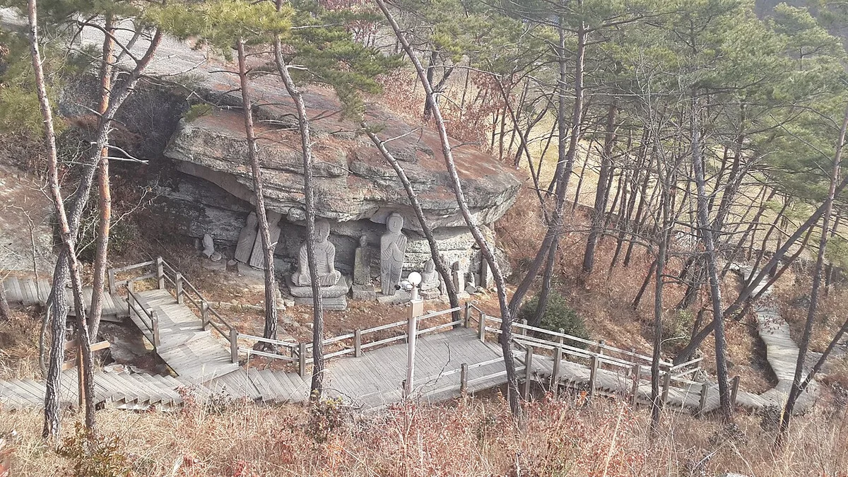 앙상한 소나무 숲 사이 바위 아래 석불이 모인 곳으로 이어진 나무 계단