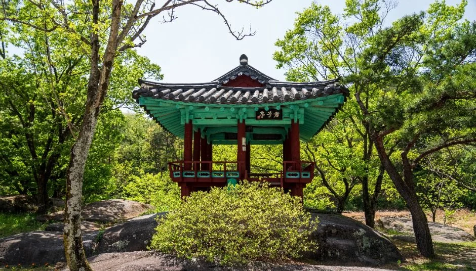 초록 지붕 단청의 작은 정자와 바위
