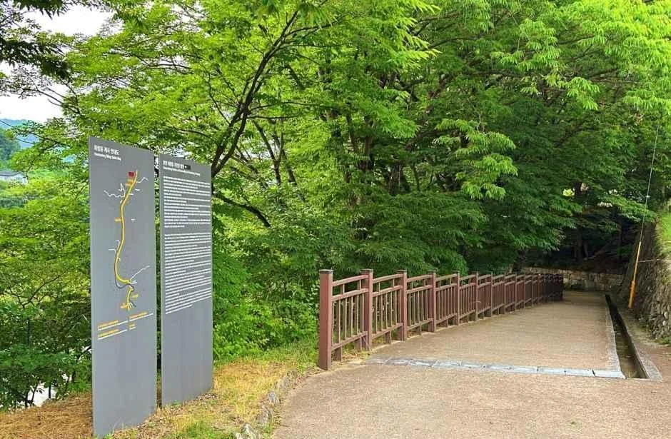 탐방로 노선도가 그려진 안내판과 흙길