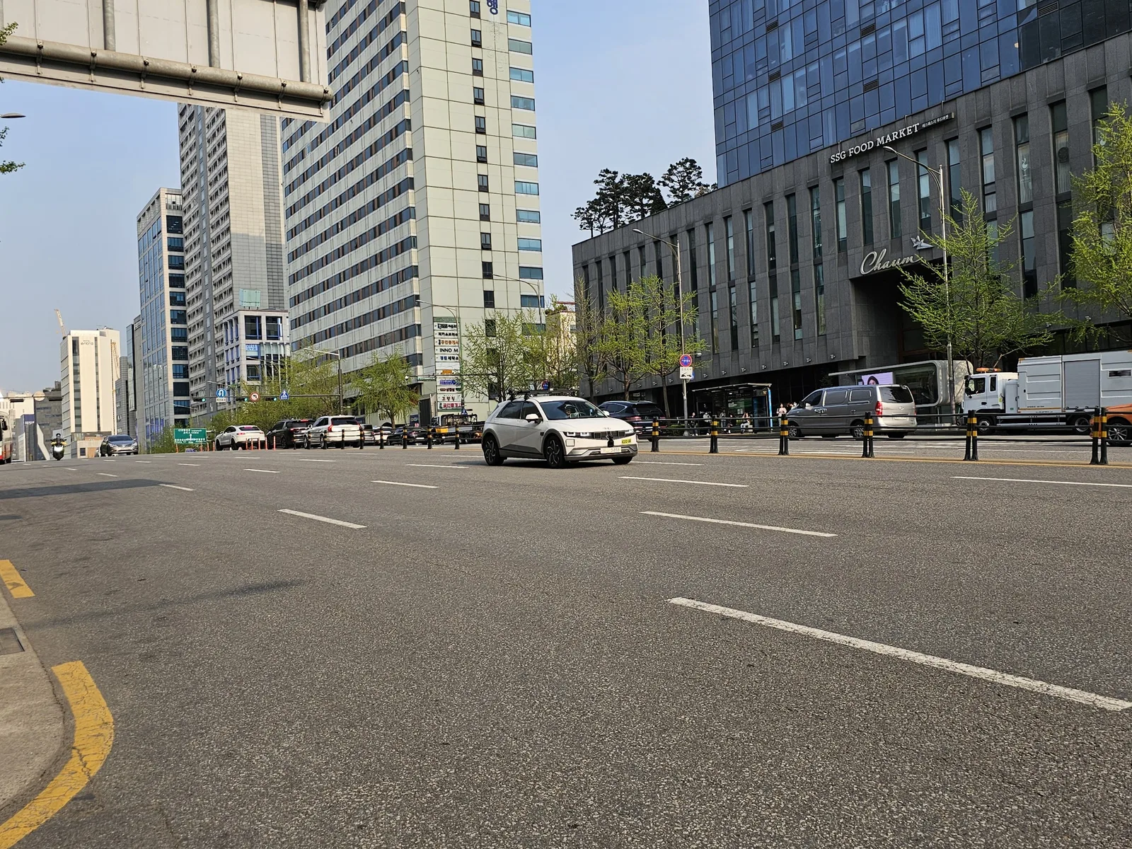 루프에 라이다·카메라 센서 랙을 얹은 흰색 현대 아이오닉5 로보택시가 서울 강남 도심 교차로에서 신호 대기 중인 모습