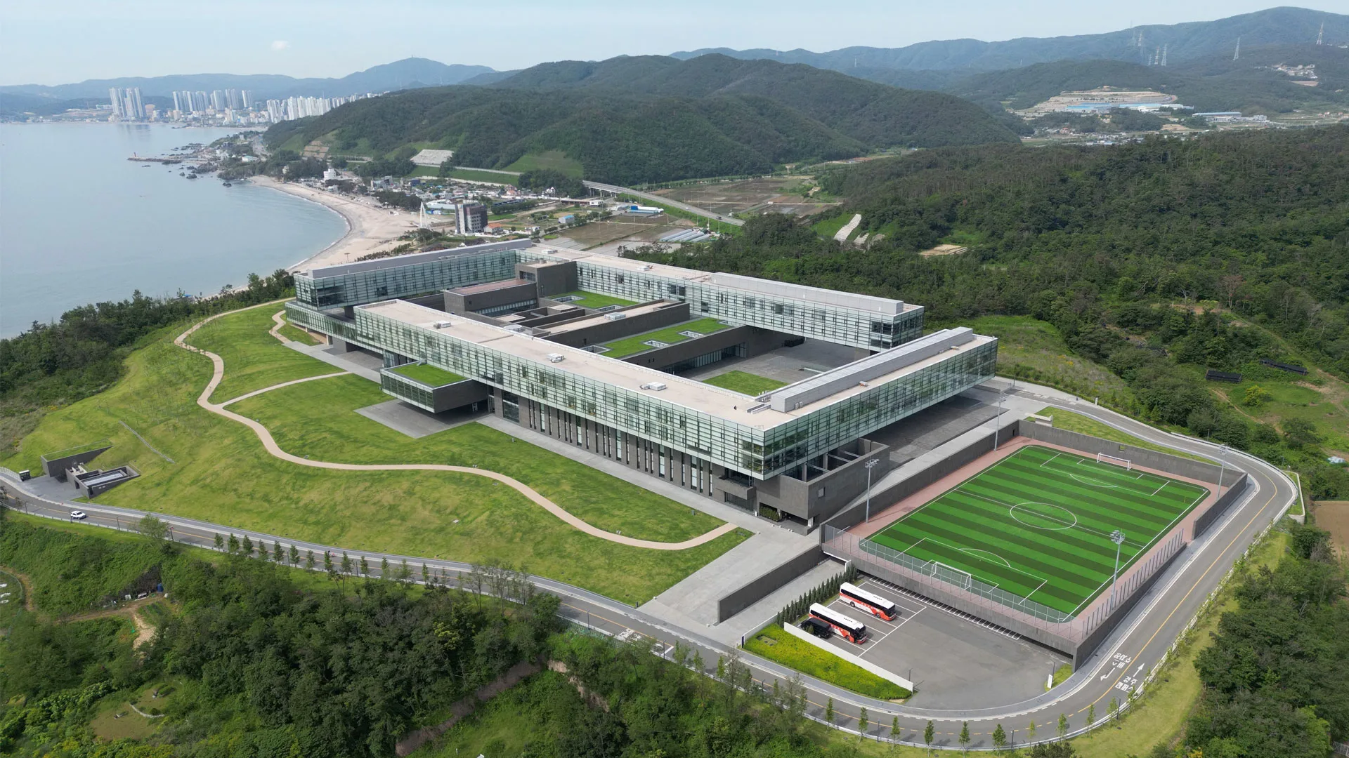 경북 경주 글로벌상생협력센터(GPC) 항공 전경, 바다와 인접한 통유리 건물과 축구장