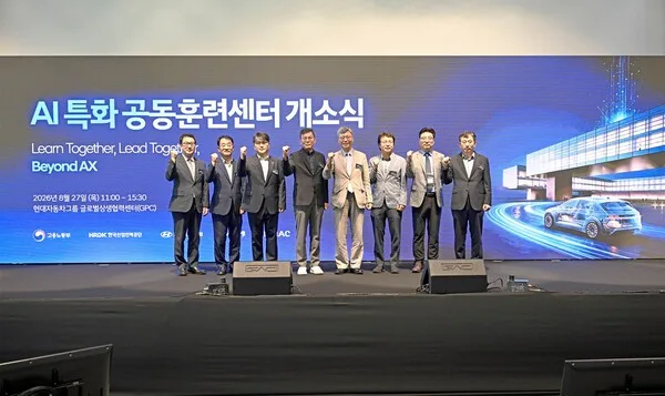 AI 특화 공동훈련센터 개소식 무대 위 기념촬영, 관계자 8명이 주먹을 쥐고 포즈를 취한 모습, 뒤로 슬로건 문구
