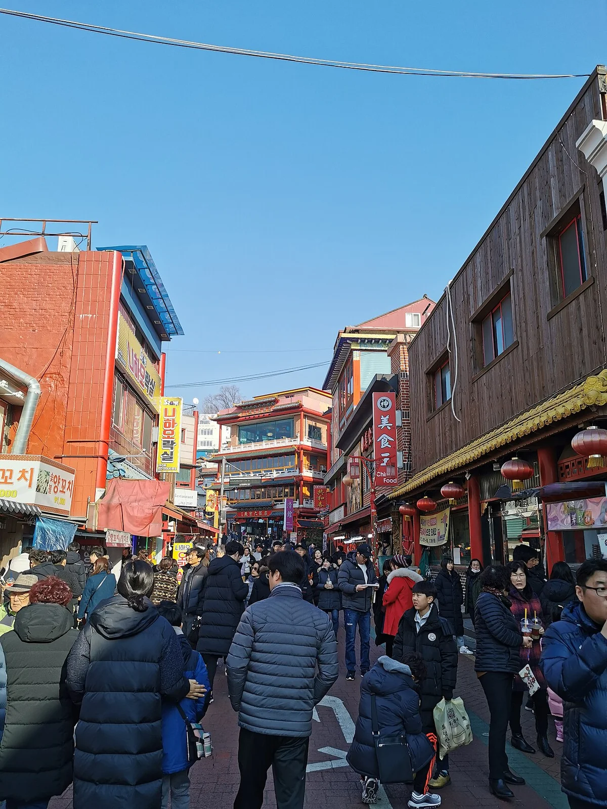 두꺼운 겉옷 차림 사람들이 오가는 차이나타운 거리