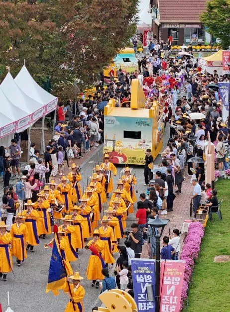 노란 의상의 퍼레이드 행렬이 지나가는 축제 거리