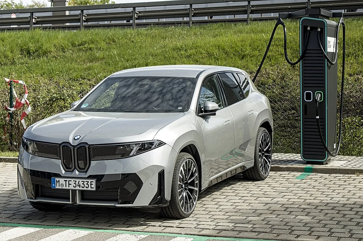 급속 충전기 옆에 서 있는 은색 BMW iX3의 전측면