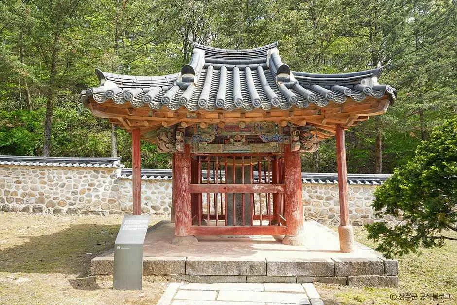 붉은 기둥과 기와지붕을 얹은 작은 전통 건물과 정원수
