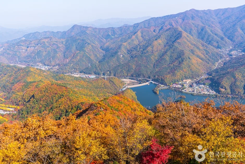 붉고 노란 단풍이 든 산자락 사이로 호수와 마을이 내려다보이는 풍경