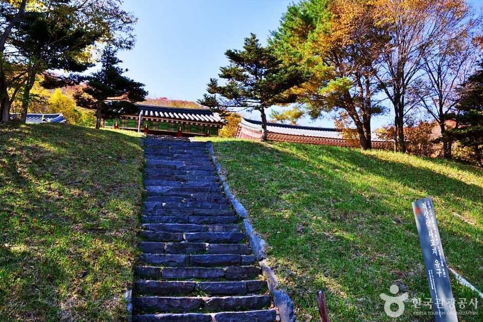 푸른 잔디밭 사이 돌계단 위쪽으로 사고지 건물 지붕이 보이는 모습