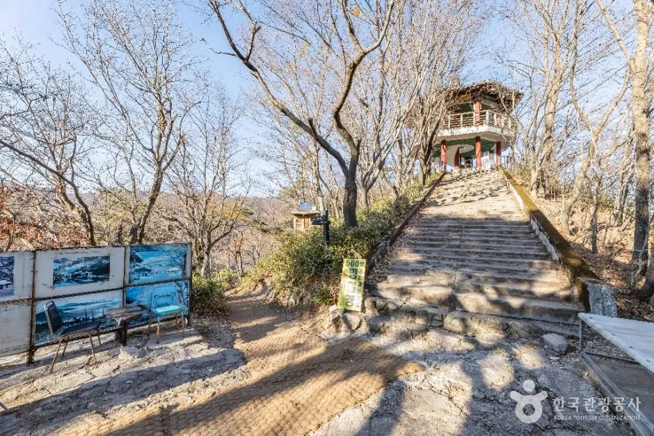 낙엽 진 숲길 계단 끝에 나무로 지은 정자형 전망 시설이 보이는 산길
