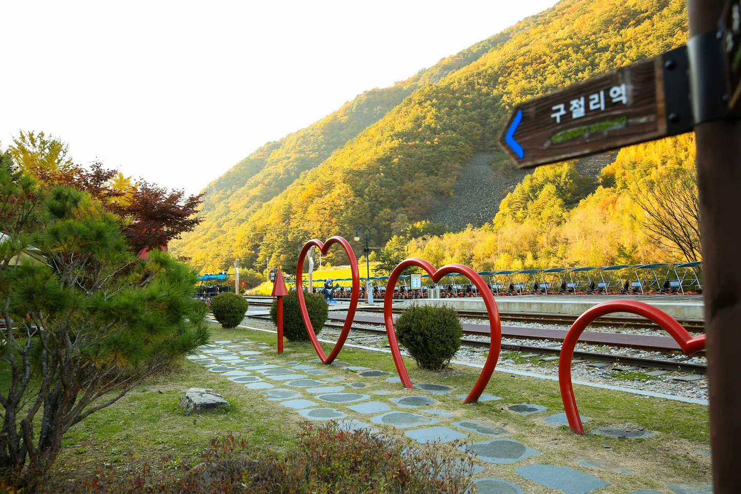 구절리역 이정표와 하트 모양 포토존 조형물, 뒤편으로 대기 중인 레일바이크들이 보인다