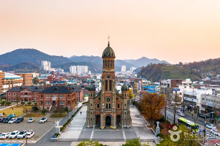 해 질 무렵 하늘이 붉게 물든 가운데 종탑이 솟은 전주 전동성당과 주변 도심 전경
