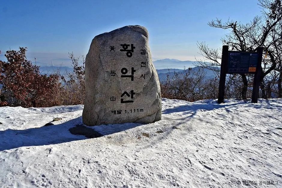 눈이 쌓인 산 정상에 세워진 황악산 정상석